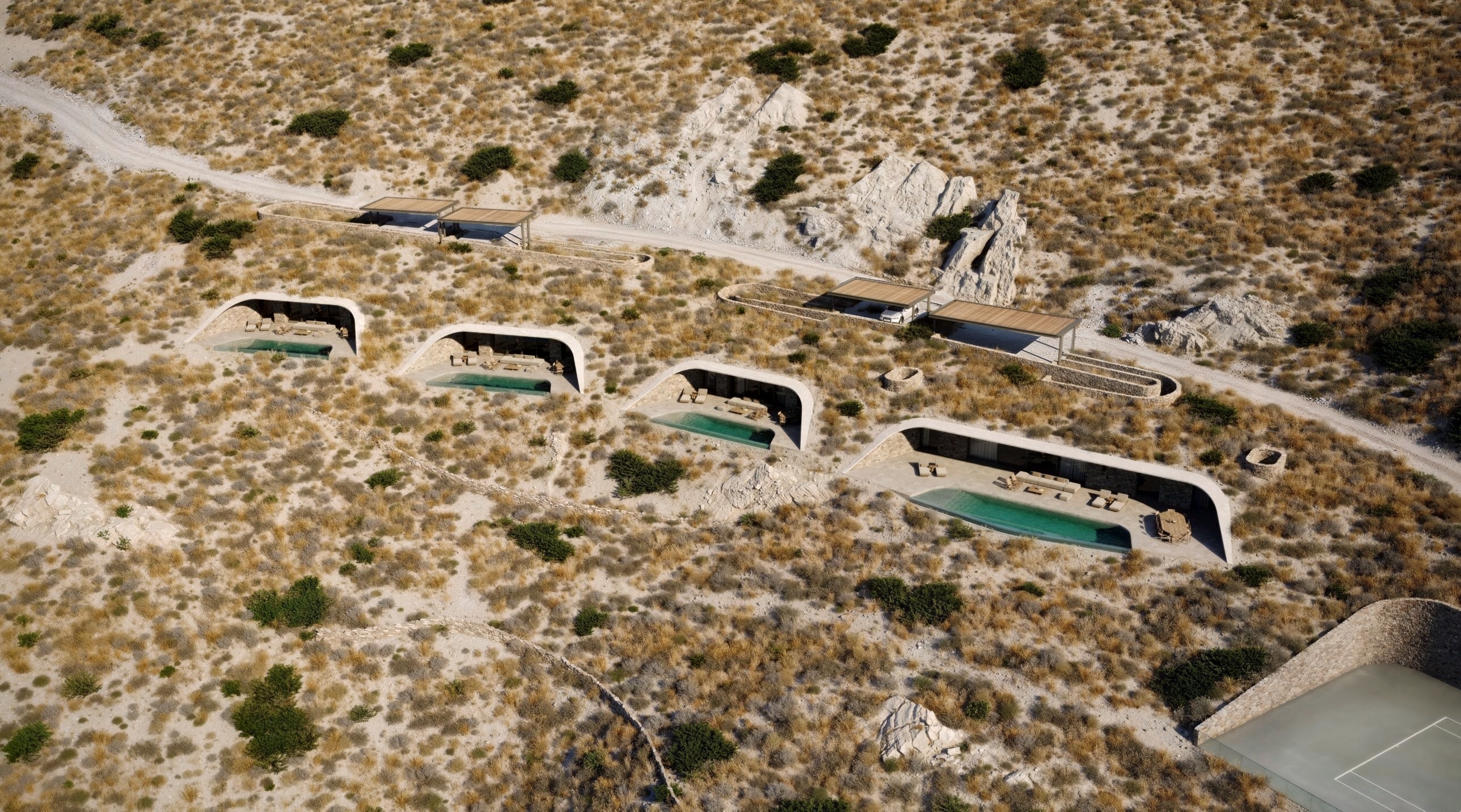 The whole complex: four residences set into the hillside above the sea. From left to right Villas A, B, C and D, with the tennis court below D. C and D are for sale.