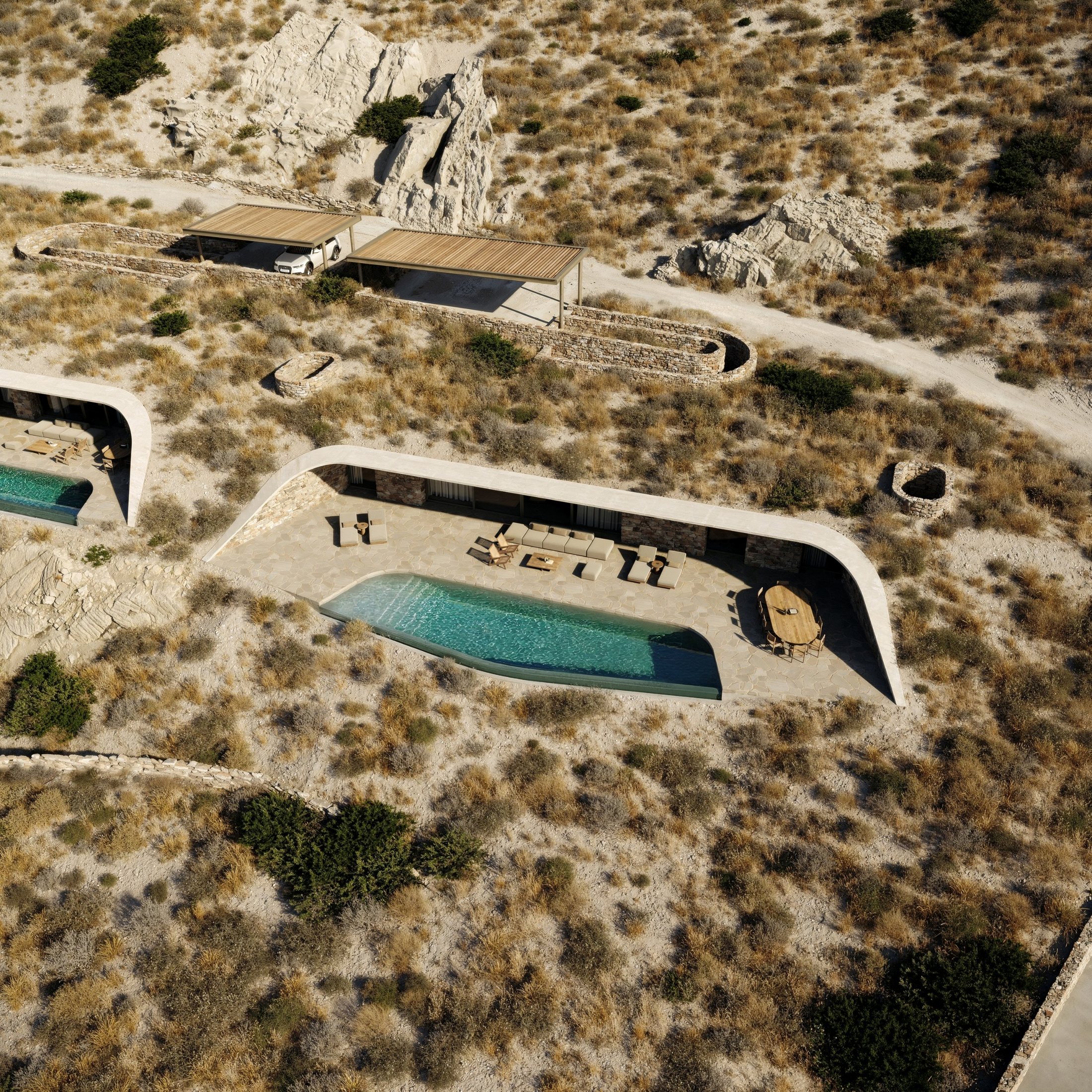 Villa D from above: the long curved roof over the stone facade, terrace, pool and dining table, parking pergolas on the road behind